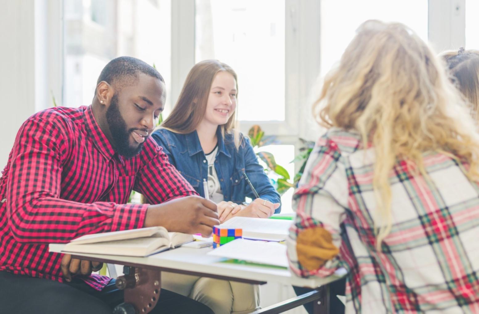 Student working through financial data analysis on laptop with notes and calculator